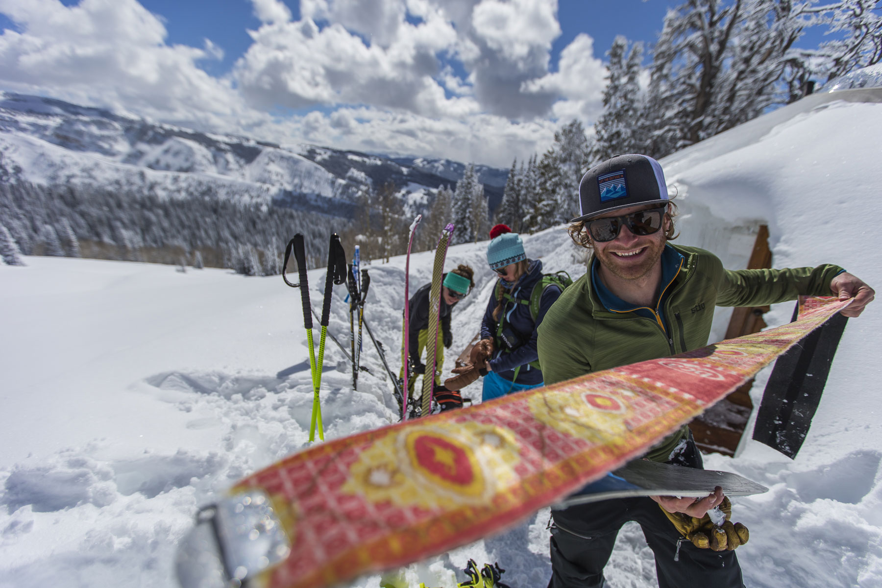 Smiling Jackson Hole Backcountry Guide Holding Climbing Skins with Two Skiers